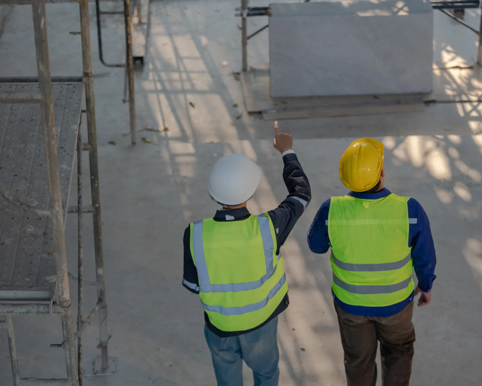 Twee mensen in werfkledij overlopen de planning op een werf