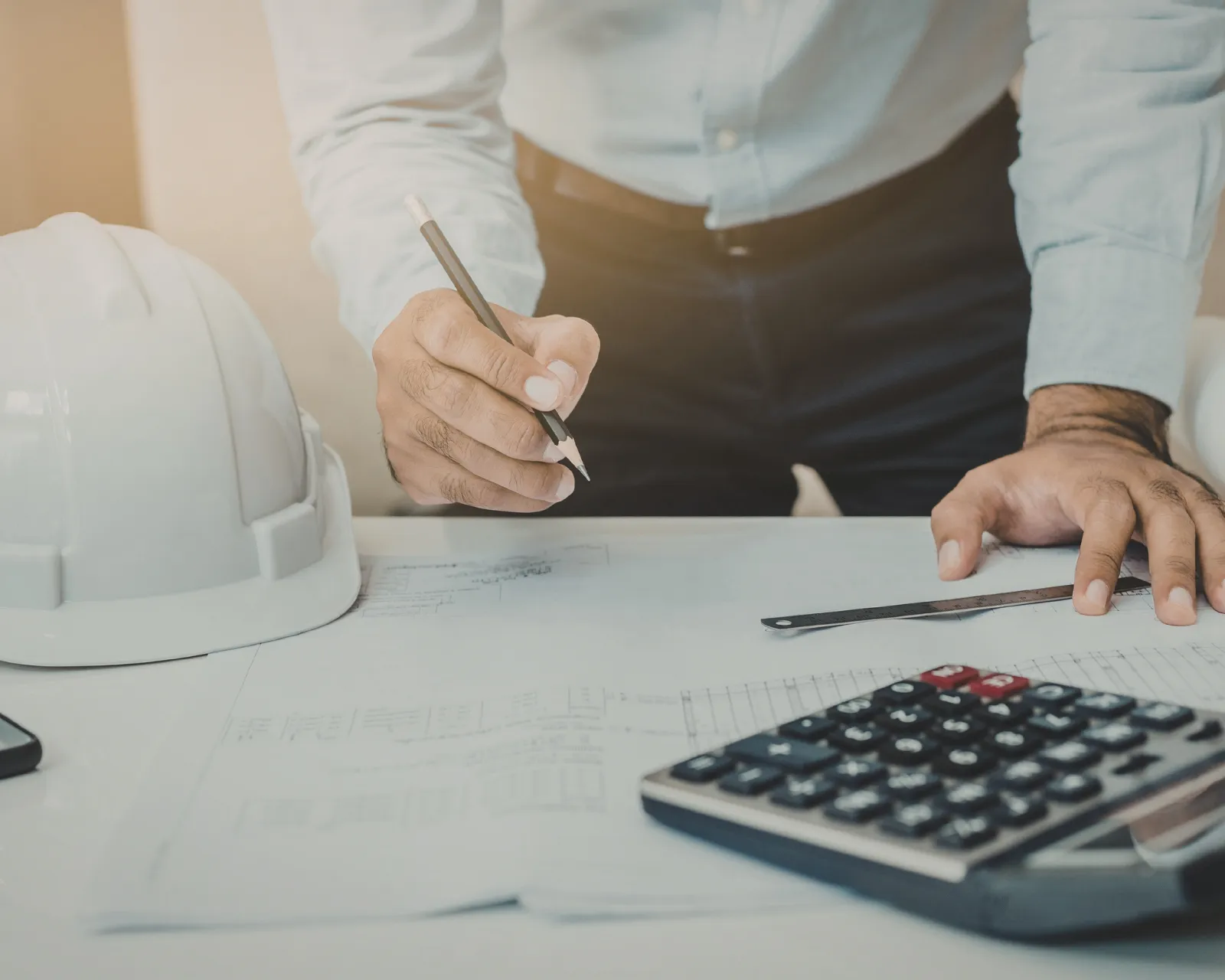 Syndicus neemt een renovatiedossier door met plannen, meetlat en rekenmachine