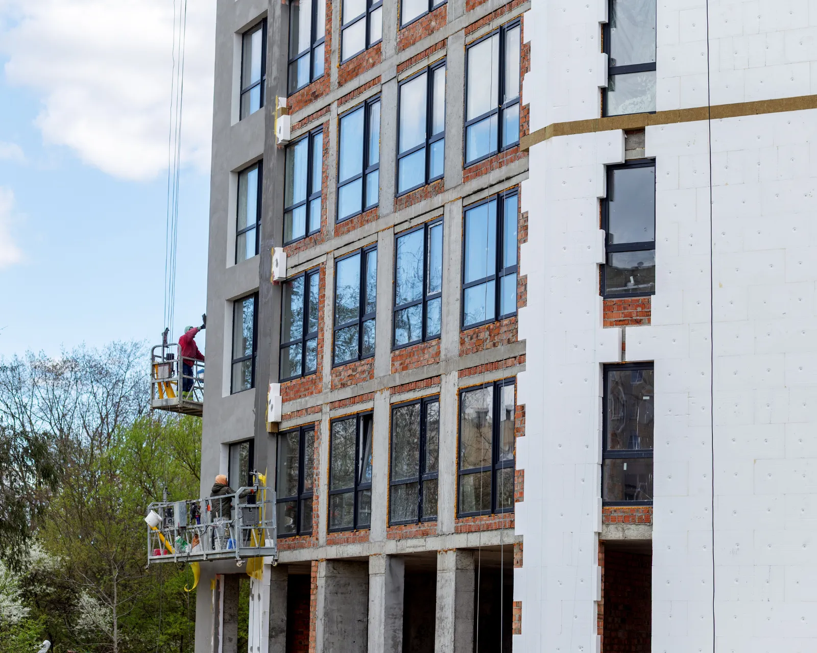 Gevelisolatie in uitvoering op een appartementsgebouw, met werkers in een hangbak
